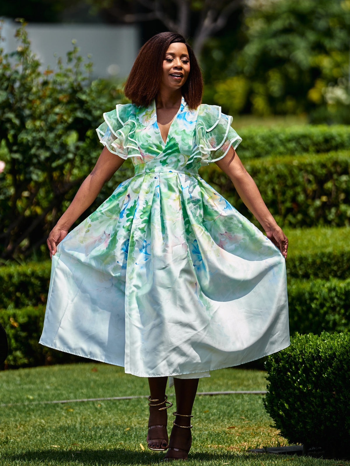 Woman in a green watercolour print dress with ruffle sleeves